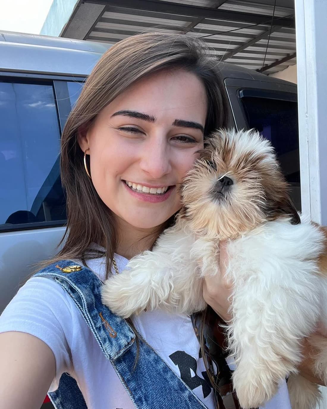 Sardie in Utah taking a selfie beside her car with Queen, a gold and white Shih Tzu puppy, held to her cheek