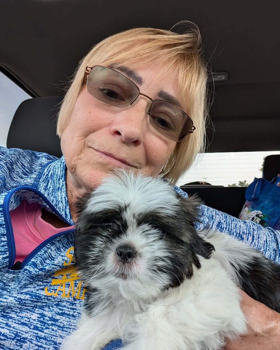 Shanice in Tennessee sitting in her car holding Kardi, a black and white Shih Tzu puppy