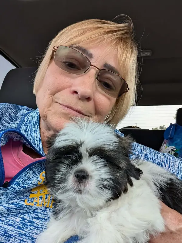 Shanice in Tennessee sitting in her car holding Kardi, a black and white Shih Tzu